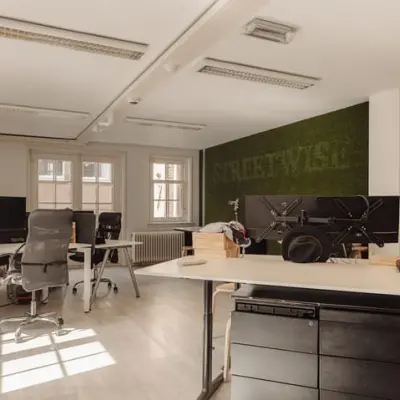 Well-lit office space for rent at Prins Hendrikkade 14 in Amsterdam Center with modern furnishings, multiple desks, and large windows.