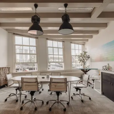 Bright and modern office to rent at Prins Hendrikkade 14, Amsterdam Center, featuring a large table and chairs near wide windows.