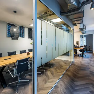 Contemporary office space in Amsterdam Center featuring a glass-walled conference room and modern furnishings, perfect for office space rental at Rapenburgerstraat 173.