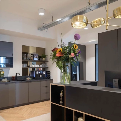Modern office space in Amsterdam Center with a reception area featuring a stylish desk, decorative lighting, and vibrant floral arrangement.
