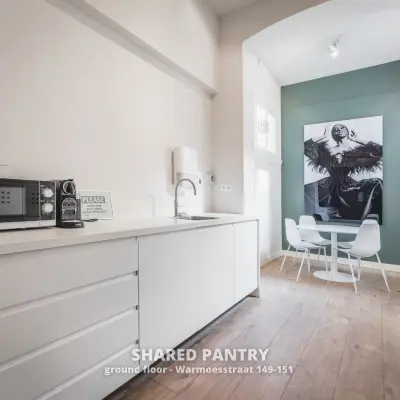 Shared pantry area at Warmoesstraat 149-151, Amsterdam Center, ideal for office space rental, with modern appliances and a cozy seating area for breaks.