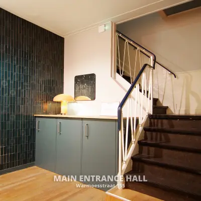 Main entrance hall of Warmoesstraat 155, featuring a staircase and cabinets, ideal for office space rental in Amsterdam Center.