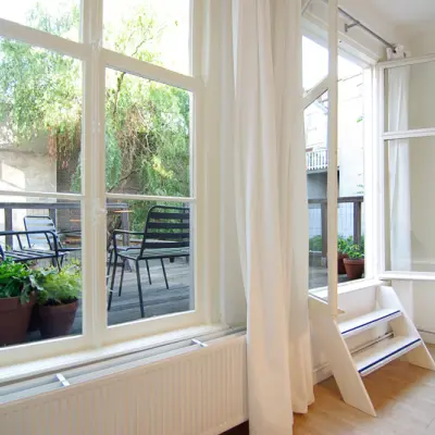 Bright office space with large windows overlooking a terrace at Warmoesstraat 155, Amsterdam Center, available for rent. Perfect for those seeking a serene and inspiring environment.