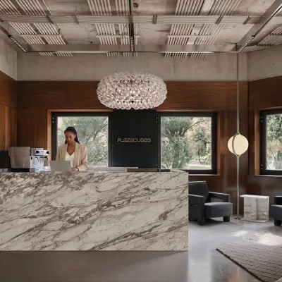 Modern reception area at Weteringschans 126, Amsterdam Center, with a marble desk and someone working at a laptop. Ideal office space rental opportunity.