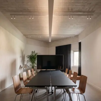 Bright, spacious meeting room with wooden chairs around a large table and a TV screen, available for office space rental in Amsterdam Center.