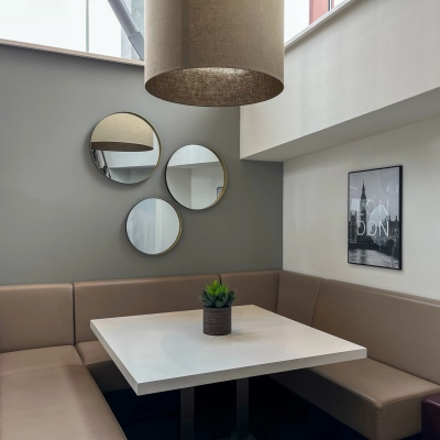 Cozy furnished office space available for rent in Amsterdam Duivendrecht, featuring a modern seating area with a table, cushions, and wall decor.