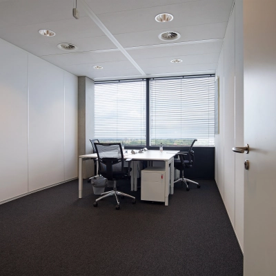 Office space with desks and chairs overlooking a cityscape at Piet Heinkade 55, ideal for those seeking office space rental in Amsterdam East.