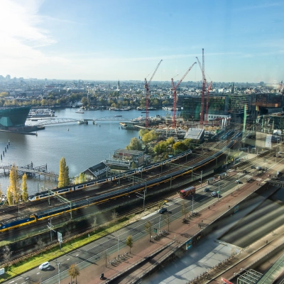 View from office to rent at Piet Heinkade 55, featuring Amsterdam East's skyline with a river, roads, and distant buildings.