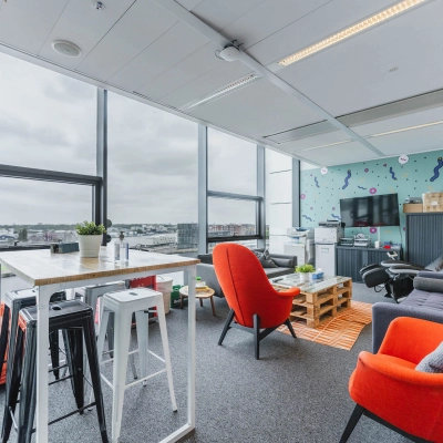 Furnished office space at Piet Heinkade 95B, Amsterdam East with vibrant seating, a wooden table, and large windows offering scenic views; perfect for office space rental.