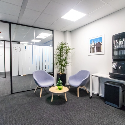 Modern office space in Amsterdam East with lounge chairs, a coffee machine, and a small table, perfect for short breaks. Ideal for those seeking office space rental.