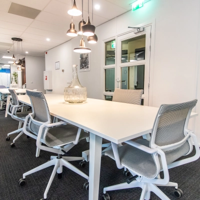 Spacious, well-lit office with modern furnishings in Amsterdam East; ideal for office space rental. Features sleek tables and comfortable chairs for a professional working environment.