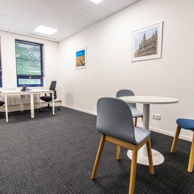 Bright office space rental at Rhijnspoorplein 10-38, Amsterdam East, with modern furnishings including desks and chairs, set against large windows for natural light.