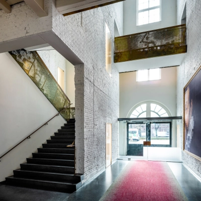 Entrance area at Sarphatistraat 370, Amsterdam East, featuring unique architecture and striking artwork - perfect for rent office space seekers.