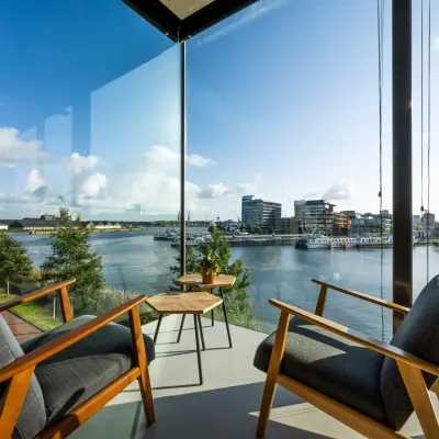 Bright office lounge area at Moermanskkade 109-113, Amsterdam, featuring two chairs and a view of the waterfront.