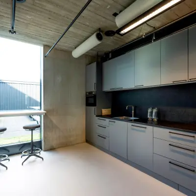 Modern office pantry with sleek cabinetry and window seating, located in Amsterdam's Houthavens area.