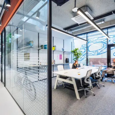Modern office space for rent at Jan van Galenstraat 335, Amsterdam New-West, featuring a stylish conference room with people engaged in discussion around a large table.