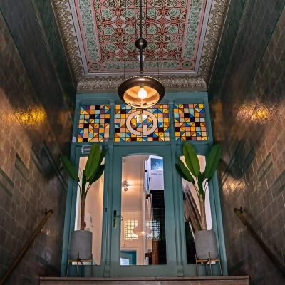 Entrance area at Emmalaan 7-9, Amsterdam Old South, showcasing decorative tiles and stained glass, perfect for those looking to rent office space.