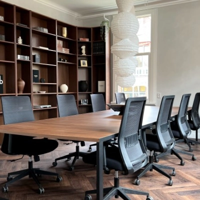 Furnished office space at Emmalaan 7-9, Amsterdam Old South, featuring a meeting table with chairs and wooden shelving in the background, ideal for office space rental.