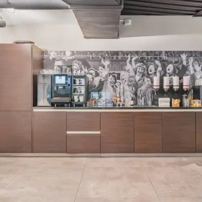 Office pantry at Olympisch Stadion 24-28 in Amsterdam Old South, featuring modern cabinetry, coffee machine, and beverage dispensers, ideal for your next office space rental.