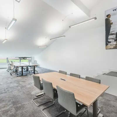 Modern office space at Olympisch Stadion 24-28 features a well-lit, open workspace with a conference table and a seating area near a window. Ideal for those seeking office space rental in Amsterdam Old South.