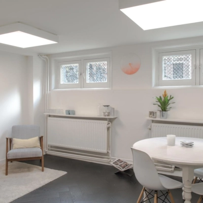 Bright office space for rent at Sophialaan 21, Amsterdam Old South, featuring a cozy sitting area with a table and chairs under skylights.