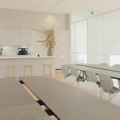 Modern office space with long tables and bar stools, ideal for meetings or casual gatherings.