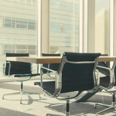 Modern conference room with large windows overlooking Amsterdam Riekerpolder, featuring a sleek table and chairs, available for office space rental.
