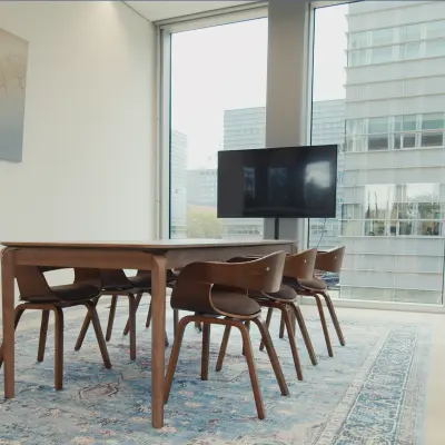 Bright conference room with a large wooden table, six chairs, and a wall-mounted screen, located in an office to rent at David Ricardostraat 1, Amsterdam Riekerpolder.