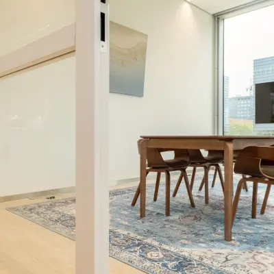 Bright office space in Amsterdam Riekerpolder at David Ricardostraat 1, featuring a conference room with a wooden table, chairs, and large windows.