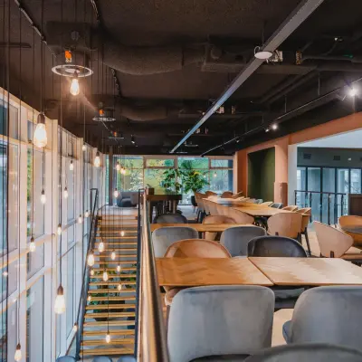 A stylishly furnished workspace at John M. Keynesplein, featuring contemporary seating and hanging lights, ideal for office space rental in Amsterdam Riekerpolder.