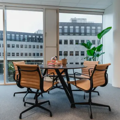 Bright office space with a round table and four chairs near large windows, located at John M. Keynesplein 4-10, an ideal spot for those seeking office space rental in Amsterdam Riekerpolder.