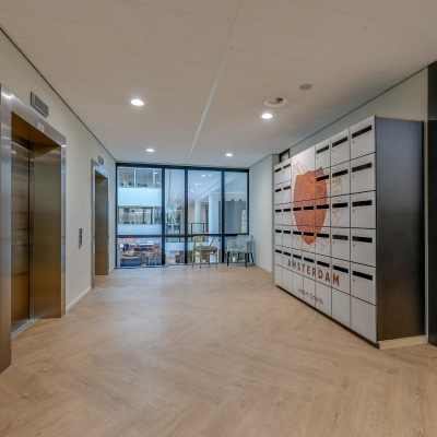 Office entrance in Amsterdam Riekerpolder with modern design, featuring an elevator and Amsterdam-themed decor, available for office space rental.