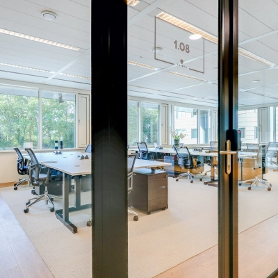 Spacious office space to rent in Amsterdam Riekerpolder, featuring large windows, multiple desks, and ergonomic chairs, offering a bright and professional workspace.