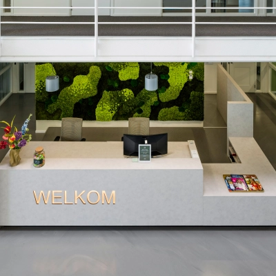 Modern reception area with a green wall and welcome sign at an office to rent in Amsterdam South East.