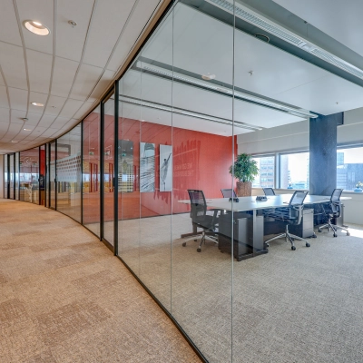Modern office space at De Entree 99-197, Amsterdam South East, featuring a glass-walled conference room with a large table and chairs, ideal for office space rental.