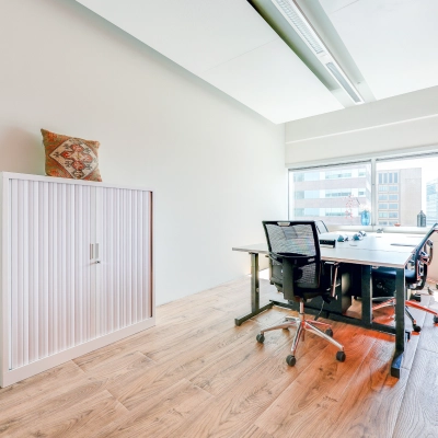 Bright office space rental in Amsterdam South East with modern furniture, a large window, and natural light.