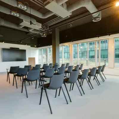 Spacious office to rent at Herikerbergweg 288, Amsterdam South East, featuring a furnished conference room with chairs arranged for presentations and large windows providing natural light.