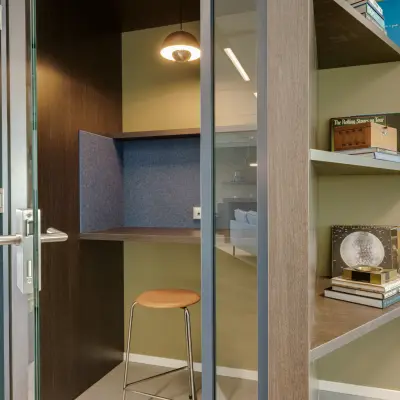 Furnished office to rent in Amsterdam South East, Herikerbergweg 288, featuring a cozy work nook with a stool and shelves integrated into the modern design.