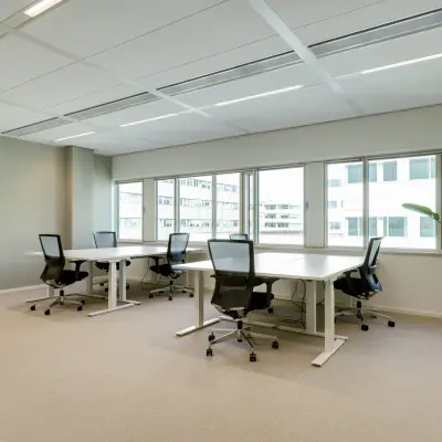Bright office space at Herikerbergweg 288, Amsterdam South East, featuring large windows and furnished with desks and chairs, available for rent.