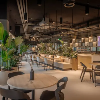 Spacious and modern furnished office space for rent at Herikerbergweg 290, Amsterdam South East, featuring stylish seating and lush greenery, ideal for collaborative workspaces.