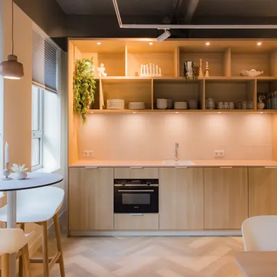 Modern furnished pantry with light wood cabinets, open shelves, and a small round table. Ideal for office space rental in Amsterdam South East.