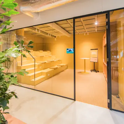 A modern interior space at Hullenbergweg 109-135, Amsterdam South East, ideal for office space rental. It features a tiered seating area and a small table, with plenty of natural light.