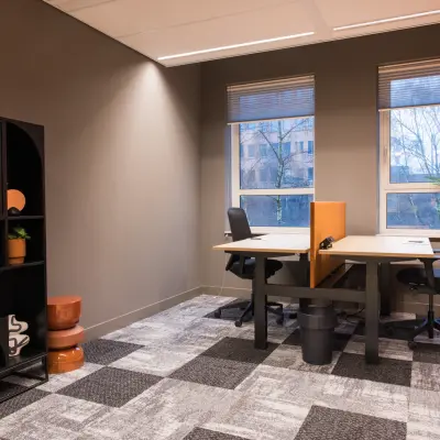 Bright office space with two desks and chairs, natural light from large windows, and contemporary decor at Hullenbergweg 109-135 in Amsterdam South East. Ideal for office space rental.