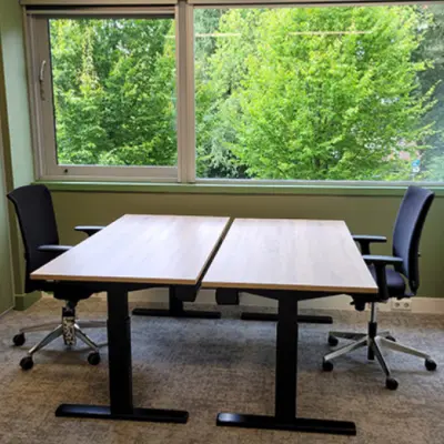 Bright office with two desks and chairs by a large window overlooking greenery, suitable for office space rental at Johan Cruijff Boulevard 89, Amsterdam South East.