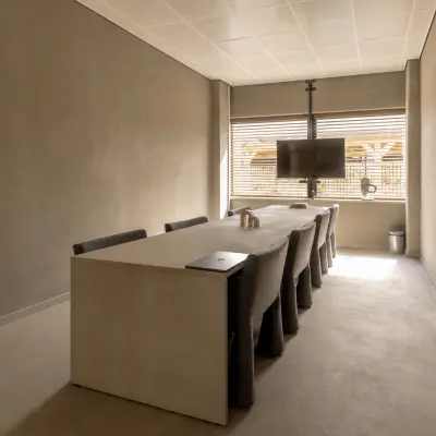 A conference room at Luttenbergweg 8, Amsterdam South East, featuring a large table, several chairs, and a mounted screen, ideal for office space rental.
