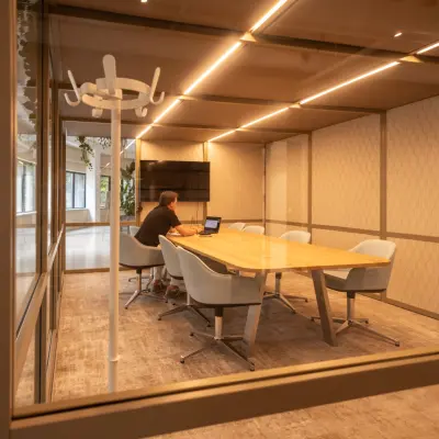 A furnished conference room at Luttenbergweg 8, Amsterdam South East, with a person working on a laptop. Ideal for office space rental or as an office to rent.