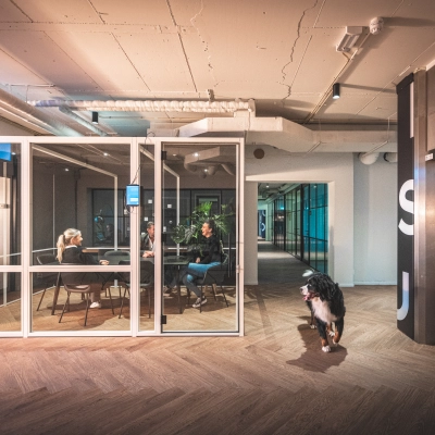 Modern office interior at Luttenbergweg 8, Amsterdam South East, featuring a meeting room with people engaged in discussion, highlighting a vibrant option for office space rental.