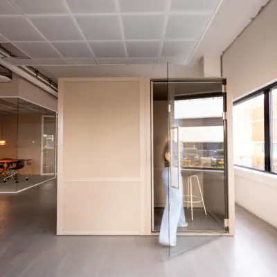 Office space at Luttenbergweg 8, Amsterdam South East, featuring a person entering a private pod with a stool nearby, available for rent.