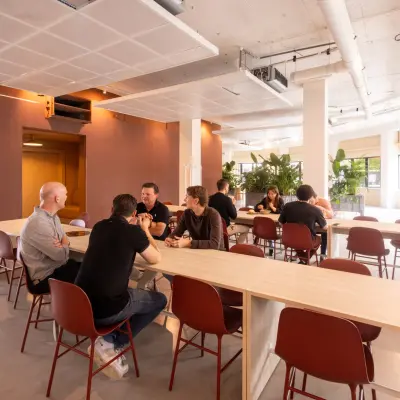 Modern furnished office space at Luttenbergweg 8, Amsterdam South East, featuring people engaged in collaborative work at tables, ideal for office space rental.