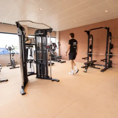 Office gym at Luttenbergweg 8 with fitness equipment and a person working out, ideal for office space rental in Amsterdam South East.